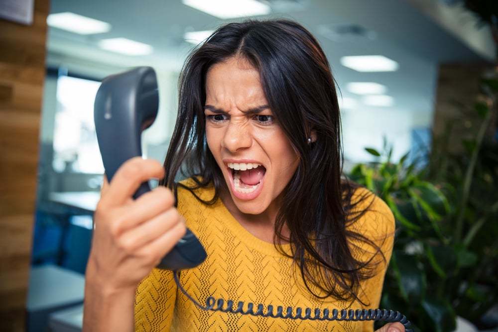 An angry businesswoman is shouting on the phone. She is unhappy with the service she has received and wants to complain aggressively.