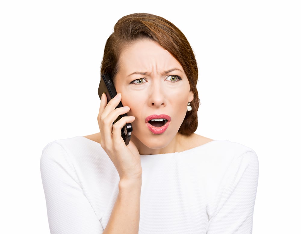 Closeup portrait of a young businesswoman having a difficult conversation with a business on her mobile phone. Negative emotions and facial expressions.