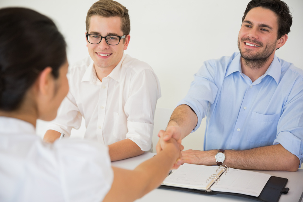 2 male member of an outsourced human resources provider greeting female client in office meeting.