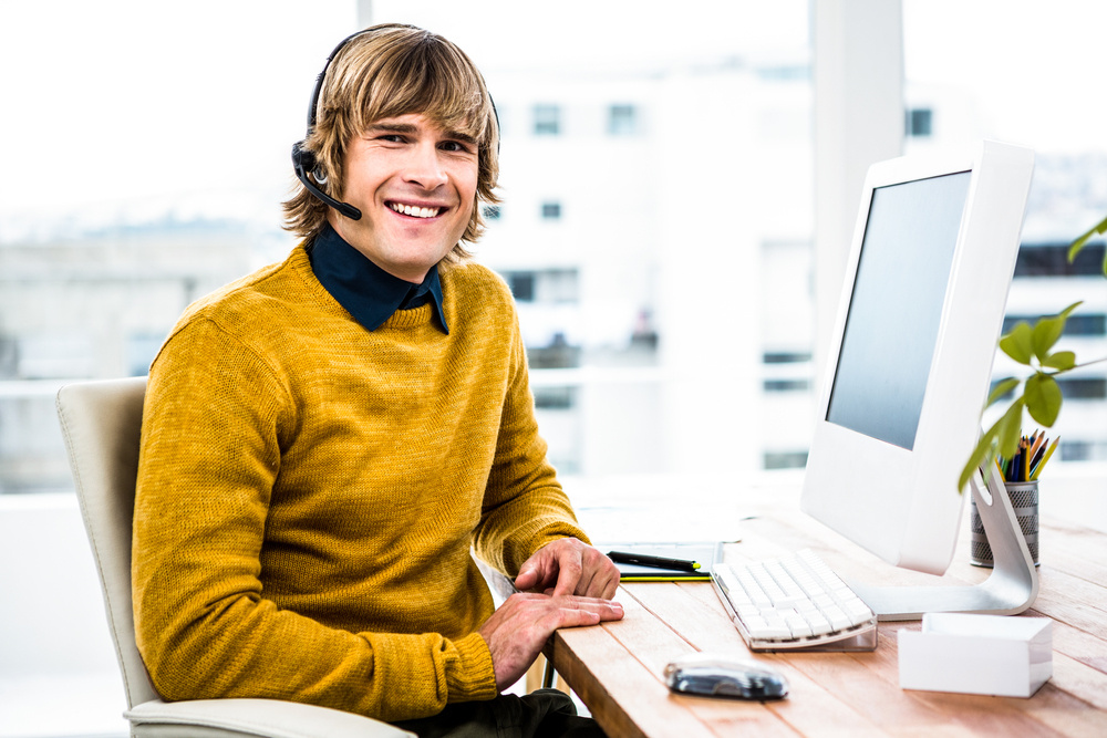 Smiling businessman using headset in his office